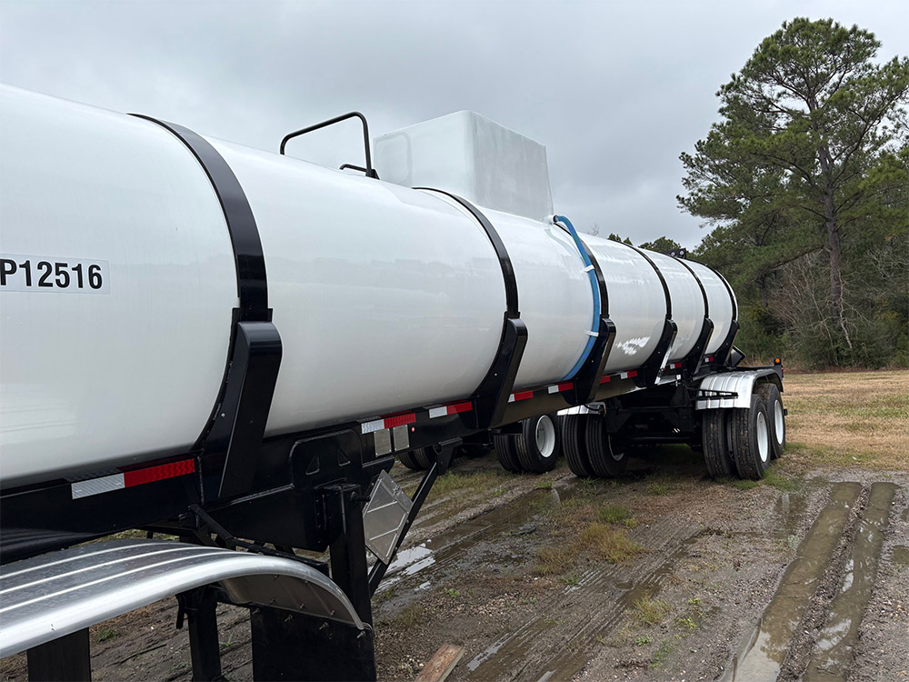 White vacuum tank trailer from Poly-Coat Systems shown from the side with the full tank body and chassis visible.